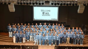 College student summer missionaries pose for a picture standing on stage